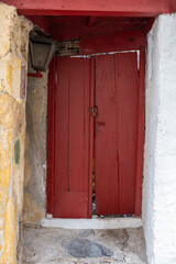 Wooden red color entrance door, locked closed. Traditional house facade, old town of Plaka, Athens Greece