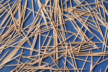 Wooden toothpicks on blue background, flat lay