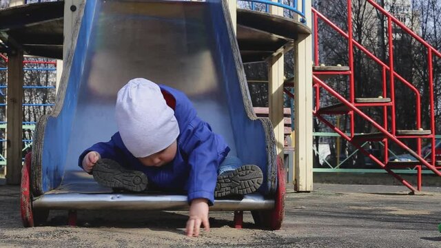 A little boy walks in the playground in the spring.