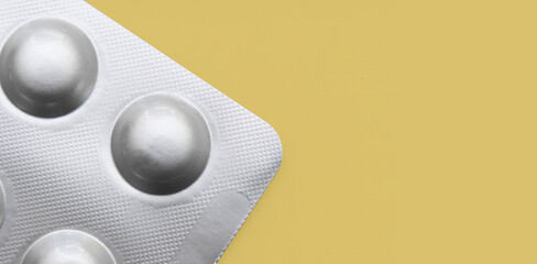 Tablets in a new silver blister pack on a yellow background. Place for text