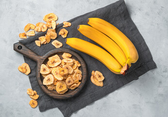Fruit, natural dessert: banana chips. Pieces of dried banana and fresh fruit on a gray background.