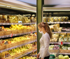 Woman buying fruits at the market.Supermarket shopping, face mask