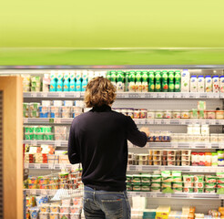 Young man shopping in supermarket, reading product information
