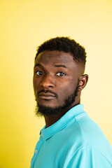 Obraz premium Portrait of young African man isolated over yellow studio background with copyspace.