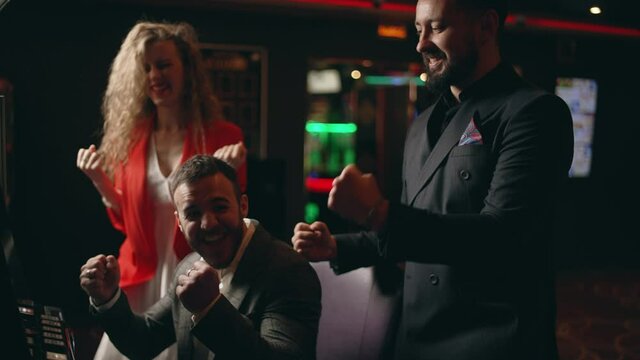 Group of young people are rejoice in victory the jackpot in a slot machine. Friends are enjoying playing at the casino. Concept of casino gambling or entertainment.