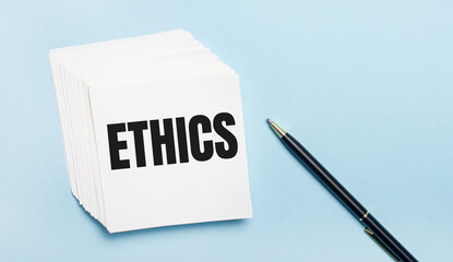 On a light blue background, there is a black pen and a stack of white note paper with the text...