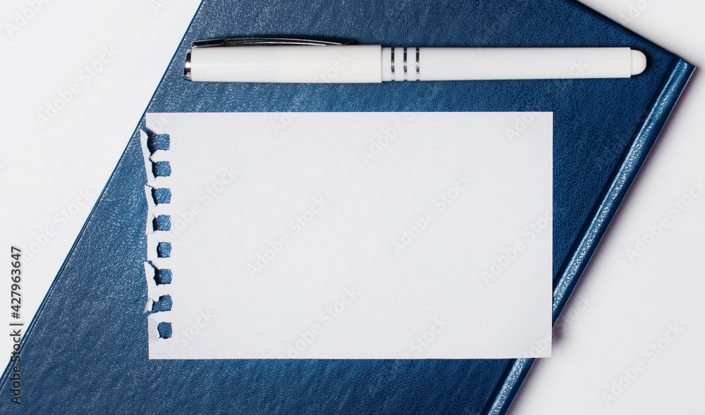 Aufkleber a blue diary lies on a light background. it has a white paper on it and a blank sheet of paper with 