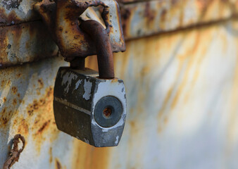 Rusty old padlock on metal gate closeup. Dirty lock on closed Grey painted front door. Protection, security and safety concept. Private property entrance. old rusty iron texture. space for text