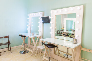 Empty woman makeup place with mirror and bulbs. Workplace makeup artist in modern makeup room. Barbershop interior. Dressing room with makeup mirror and table. Modern classical style interior design.