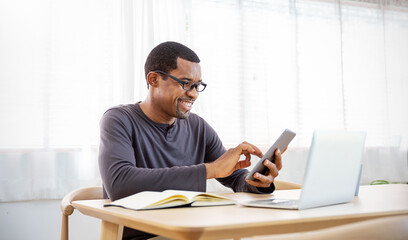 Portrait of happy business African black man with casual cloths working in home office desk using phone computer. Small business employee freelance online sme market e-commerce telemarketing concept