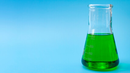 Chemical research, lab test and scientific experiment concept with green coloured liquid  solution in glass erlenmeyer conical flask isolated on blue laboratory background with copy space