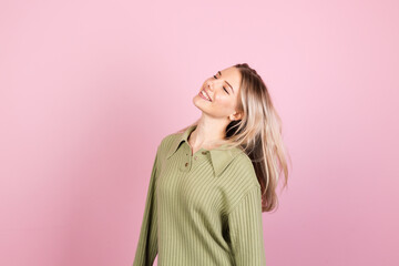 Pretty european woman in casual sweater on pink background cute smiling happy positive dancing moving