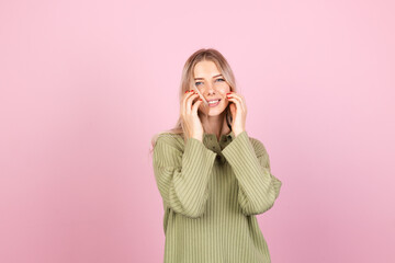 Pretty european woman in casual sweater on pink background cute smiling happy positive dancing moving