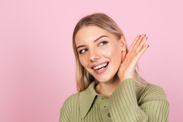 Pretty european woman in casual sweater on pink background curious try to hear what you saying with...