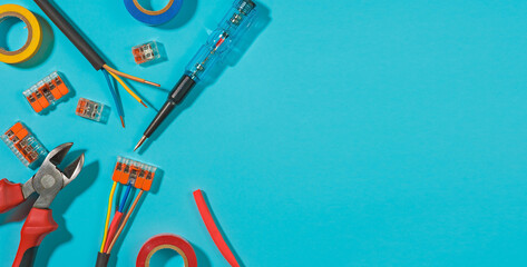 Layout of tools and equipment for electrical repair at home or office on blue background. Spare parts, connecting terminals and wires, wire cutters with screwdriver, top view with copy space for text