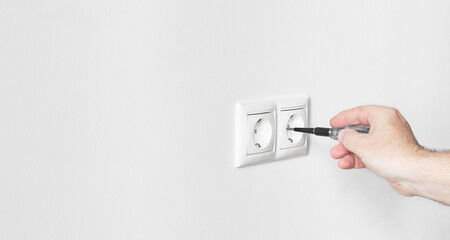 Installing or mounting electrical outlets on a neutral light gray plastered wall. European electrical outlet close-up with copy space. Repair work on electricity in a home or office