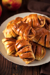 Homemade rolls buns with apples and cinnamon on brown wooden background. Soft focus