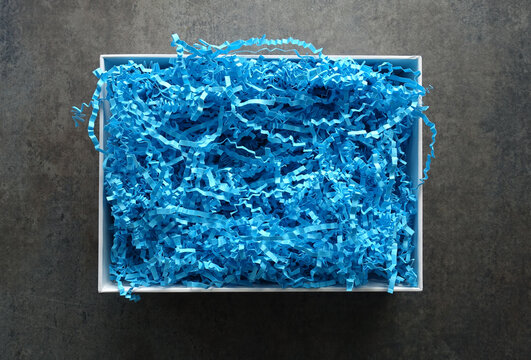 White Gift Box filled with Blue Crinkle Paper against a Gray Background