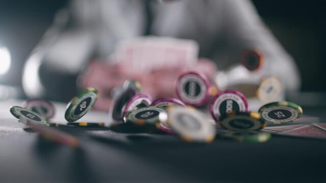 Casino chips and playing cards are falling against the background of a player with cards in slow motion. Concept of gambling or poker and entertainment.