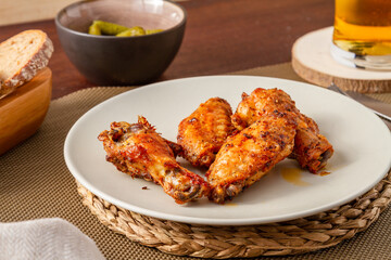 plate with roasted chicken wings, bowl of pickles and pint of beer