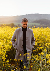 Portrait of a mature man in stylish gray jacket standing in a field surrounded by flowers.
Conceptual of lifestyle, spring