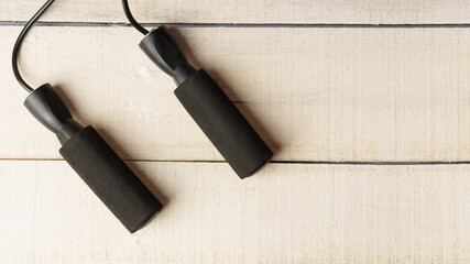 skipping rope on a white wooden background. black rope handles