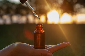 Female holding a dropper bottle of herbal essential oil. Flower therapy - BACH.