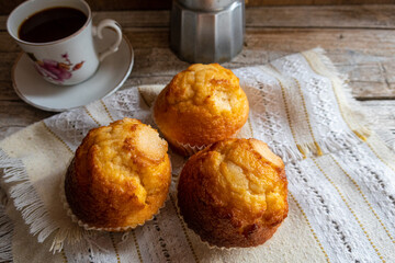 Cupcakes accompanied with coffee, on a napkin, on a rustic wooden background. 
