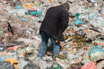 Ukraine, Tatarbunar - 13.04.2021: A man collects garbage at the city dump.  City dump.