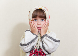 Portrait of small pretty girl in traditional ukrainian style.Young beautiful girl in a  long white national shirt and traditional scarf. Ukrainian culture, ethno style.