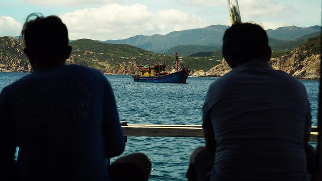 Two man on boat trip enjoy sea and shore scenery, Vinh Hy Bay, Vietnam