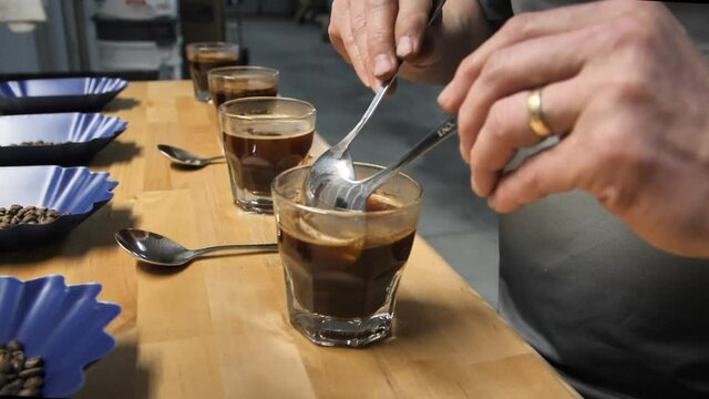 Coffee cupping, cup tasting using two spoons, slow motion close up