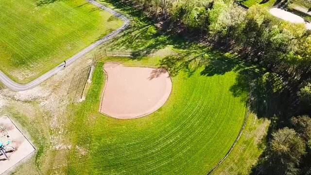 Drone orbiting around a High School baseball field. There is a playground set barely visible frame left.