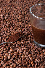 coffee beans background with coffee beans, a cup of coffee and a teaspoon of ground coffee