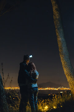 Man use smartphone Takes a selfie, photo picture. The couple stand on the background of the city lights. night time. Vertical photo. Naples. Volcano Vesuvio.
