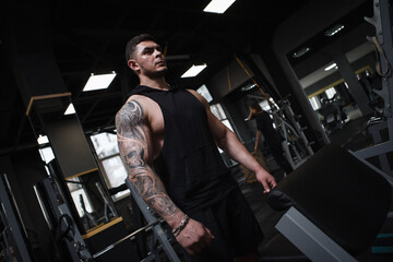 Low angle shot of a muscular tattooed bodybuilder focusing before his gym workout