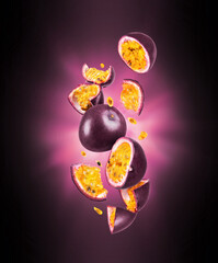 Whole and sliced ripe passion fruit in the air with flash of light in the dark