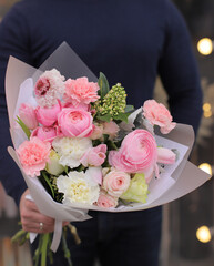 Strong man holding a delicate bouquet of beautiful flowers in his hands. Delicate flower bouquet. Wrapped flowers bouquet. Fresh beautiful flower. Man holding a big beautiful flowers bouquet.