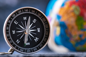 Travel planning navigation concept. Classic magnetic detail of compass on light blue with earth globe in the backround.