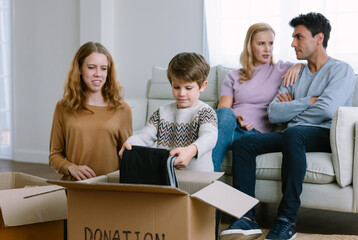 Happy volunteer caucasian family separating donations clothes in carton package donate to needy...