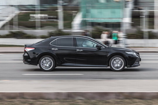 Luxury business Toyota Camry cruising the streets. Motion image of black shiny car running on the city road
