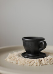 Black clay cup with napkin macrame on table. Black Ceramic Plate