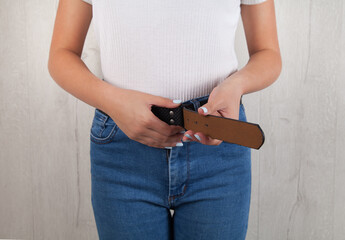 Young woman is tying a belt to her jeans.