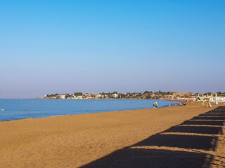 Sandy beach and surf line on a sunny, cloudless day.