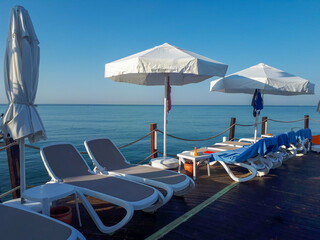 Wooden pier, beach and sun umbrellas on a sunny day.