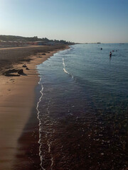 Sandy beach and surf line on a sunny, cloudless day.