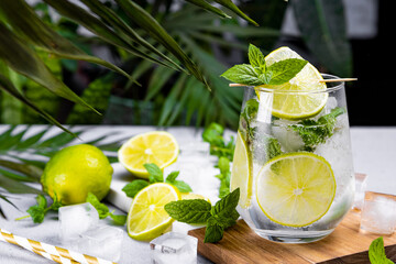 Refreshing mojito with lime, mint and ice in a glass on a summer green background, free space for...