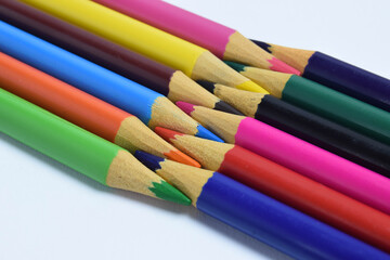 Fototapeta premium colored pencils arranged head to head isolated on a white background. wooden pencils background
