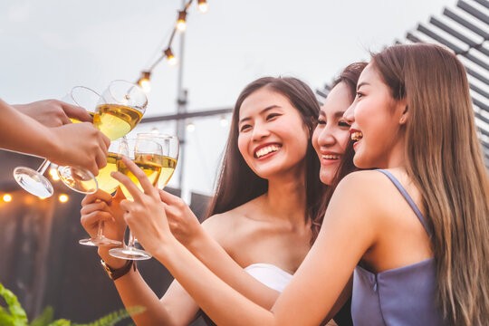 asian woman teenagers cheering and toast with white sparkling wine glass to celebrating at dinner party in summertime. celebration, relationship and friendship concept.