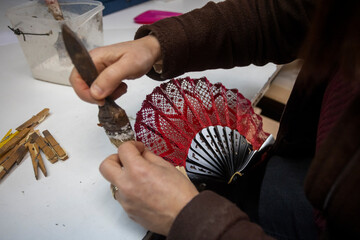 Closeup shot of a Spanish woman working at a hand fan design workshop